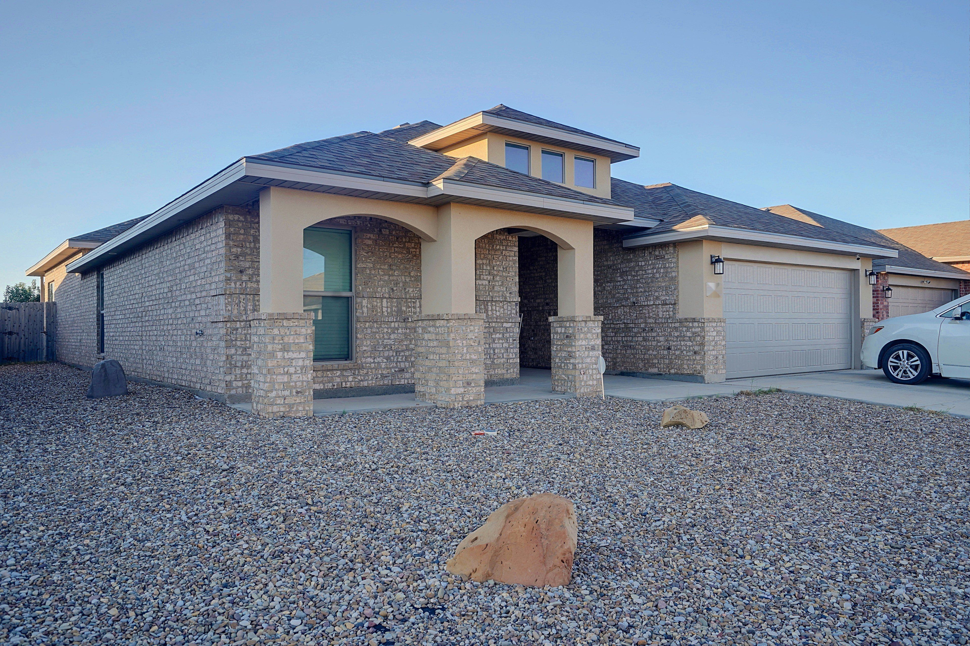 A residential house with a stone facade, a garage, and a gravel driveway.