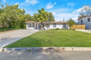 A single-story house with a front lawn, a palm tree, and a wooden fence. - Home w/ Outdoor Entertainment Area in San Antonio! (San Antonio)