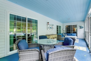 A covered patio with wicker furniture, a glass table, and a blue floor.