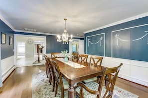 A dining room with a wooden table, chairs, a chandelier, and decorative wall art.