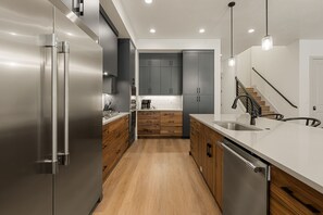 Une cuisine moderne dotée d’appareils électroménagers en acier inoxydable, de meubles en bois et d’un îlot central.