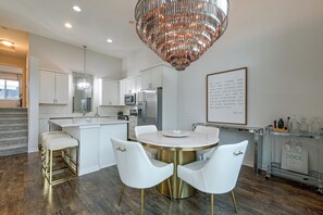 A modern kitchen with white cabinetry, stainless steel appliances, a marble island, and a chandelier. - Modern West Des Moines Townhome - Family Friendly! (West Des Moines)