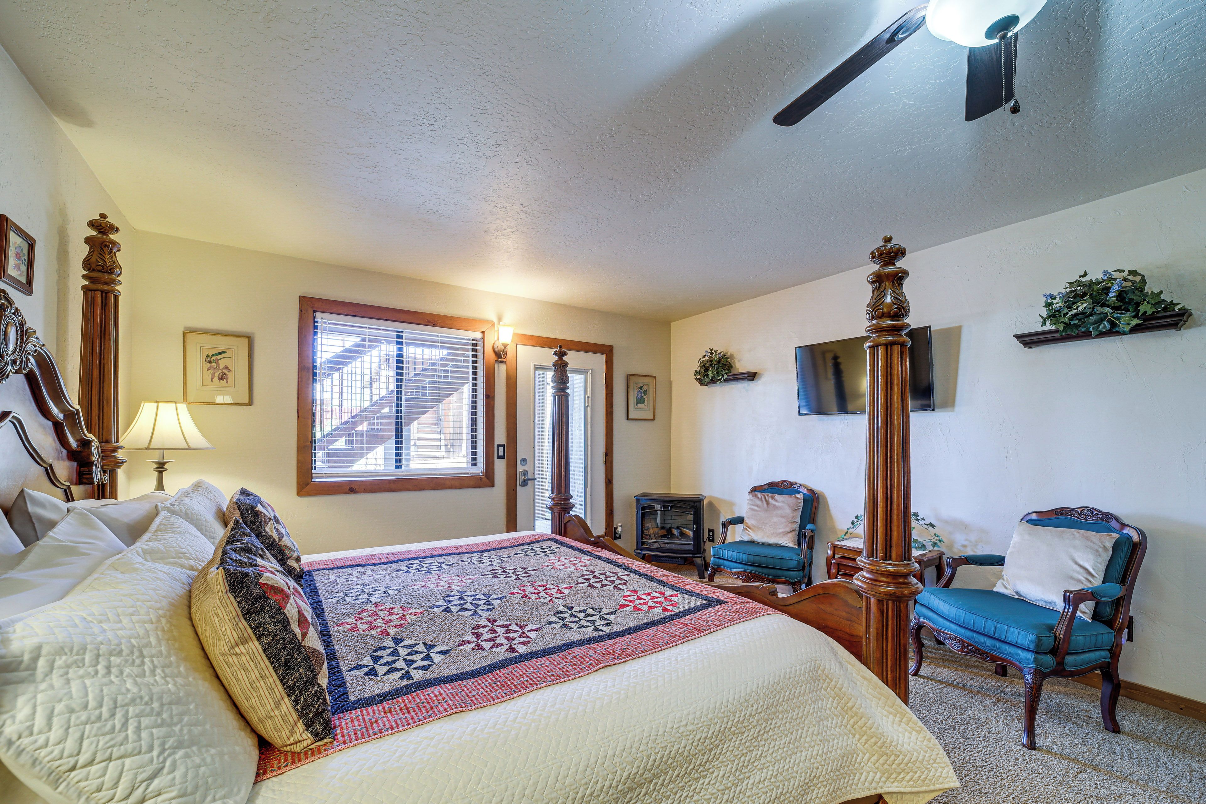 A bedroom with a large bed, a wooden chair, a television, and a fireplace.