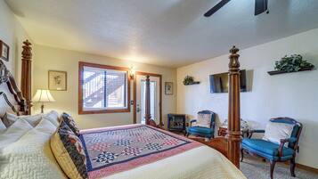 A bedroom with a large bed, a wooden chair, a television, and a fireplace.