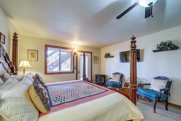 Un dormitorio con una cama grande, una silla de madera, un televisor y una chimenea.