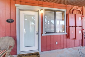 Un edificio de madera rojo con una puerta blanca, una ventana con persianas y un letrero que dice 'Juniper Room'.