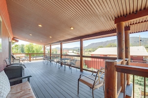 A covered outdoor deck with wooden flooring, metal chairs, and tables.