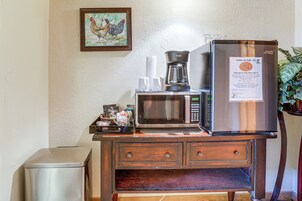 Una kitchenette equipada con refrigerador, microondas, cafetera y un pequeño bote de basura.