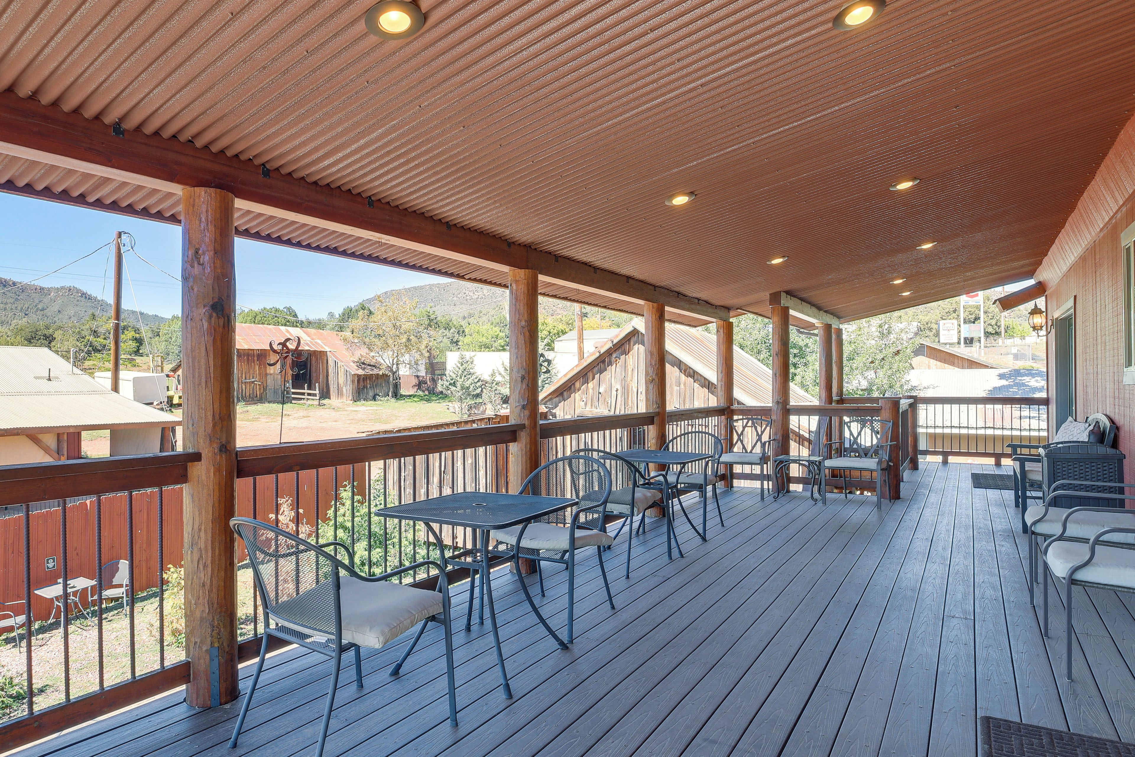 A covered outdoor patio with wooden flooring, metal chairs, and tables.