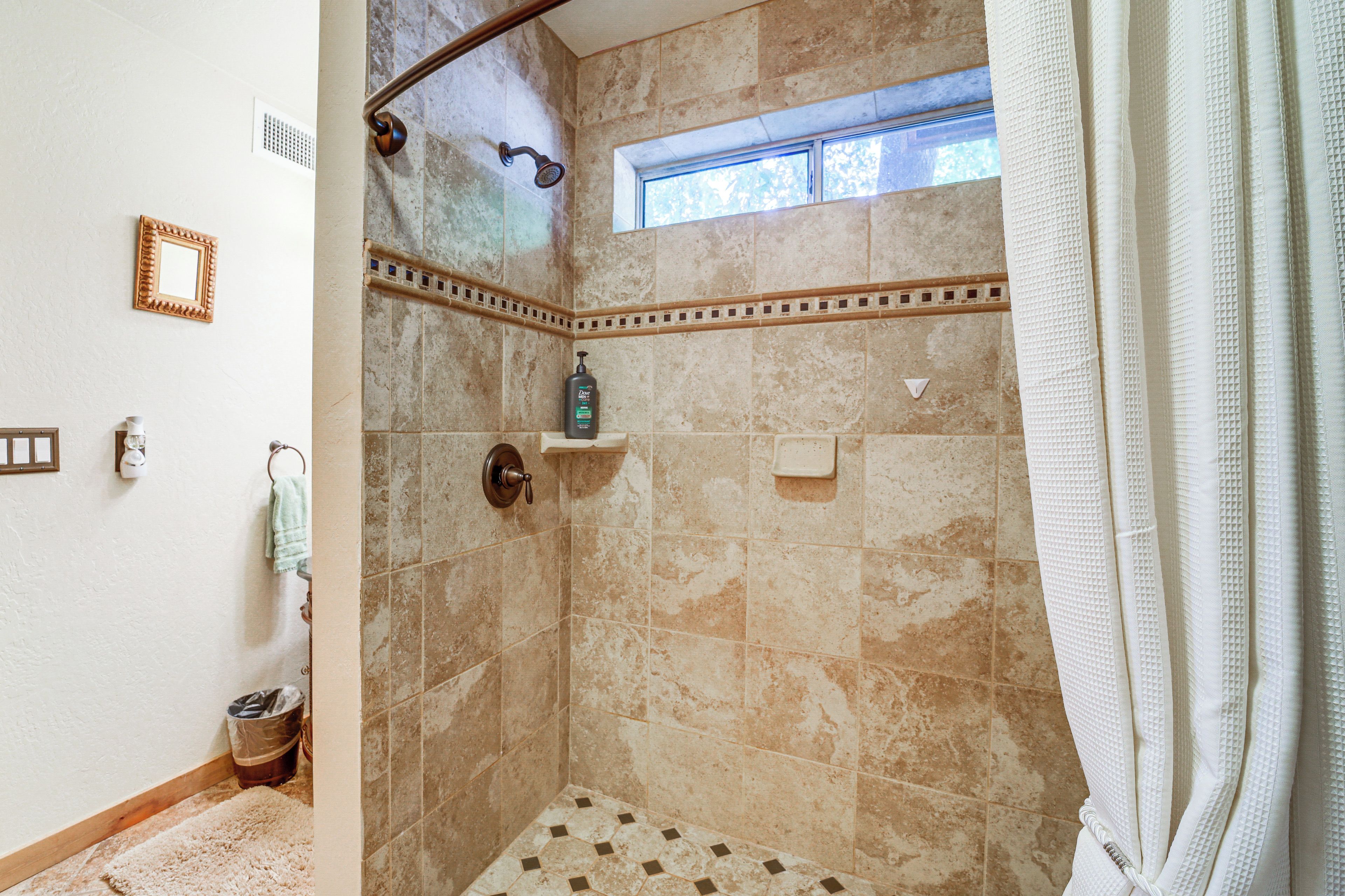 Une douche avec une fenêtre, un porte-serviettes et une bouteille de shampoing.
