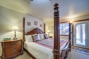 A four-poster bed with a wooden headboard, a nightstand with a lamp, and a dresser with drawers.