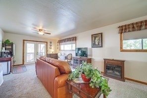 A living room with a leather couch, a television, a fireplace, and a ceiling fan.