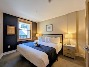 A hotel room with a large bed, two bedside tables, a window, and a door. - Mountain View | King Bed | Hot Tub (Keystone)