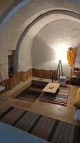 A room with a vaulted ceiling, a central seating area with a table and chairs, and a small rug on the floor.