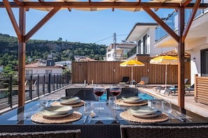 An outdoor dining area with a table set for four, overlooking a pool and a hillside. - Villa Savaya-2 Antalya (Kaş)