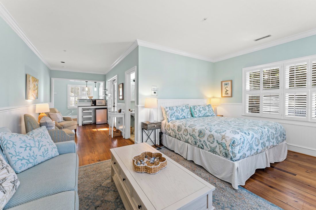 A bedroom with a bed, a sofa, a coffee table, and a desk.
