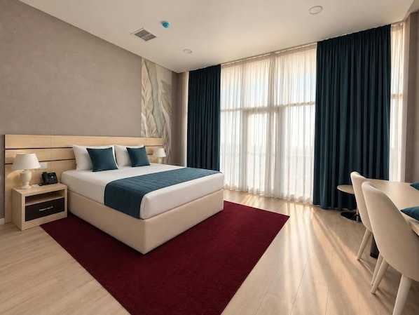 A modern hotel room with a large bed, a desk, and a chair.