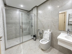 Un baño moderno con ducha envuelta en vidrio, inodoro y lavamanos.