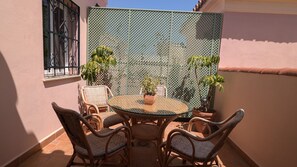 Eine Terrasse mit Korbmöbeln und Topfpflanzen.