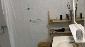 A bathroom with a shower, a sink, a mirror, and a small wooden stool.