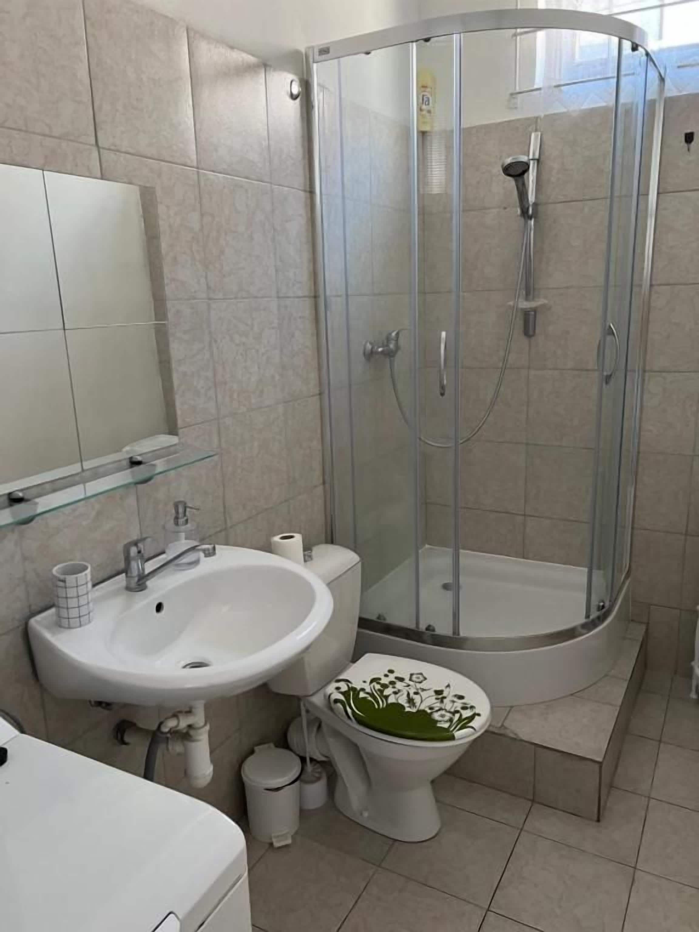 A bathroom with a glass-enclosed shower, a sink, a toilet, and a mirror.