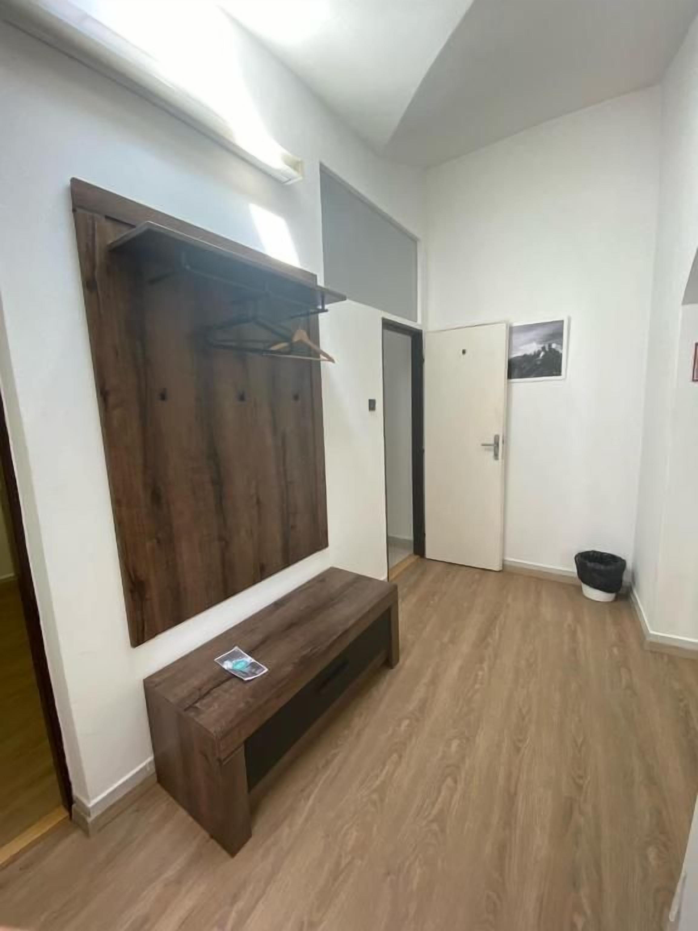 A hallway with a wooden bench, a coat rack, and a door.