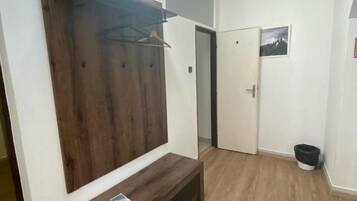 A hallway with a wooden bench, a coat rack, and a door.