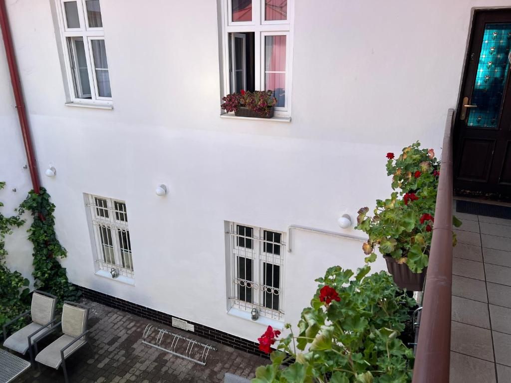 Un bâtiment blanc doté de nombreuses fenêtres, dont certaines sont ornées de jardinières, et dont le sol est recouvert de carreaux.