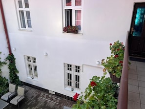 A white building with multiple windows, some with flower boxes, and a tiled floor.