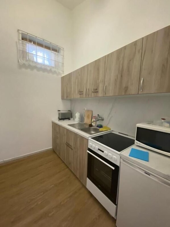 Una cocina compacta con armarios de madera, horno empotrado, microondas y fregadero.