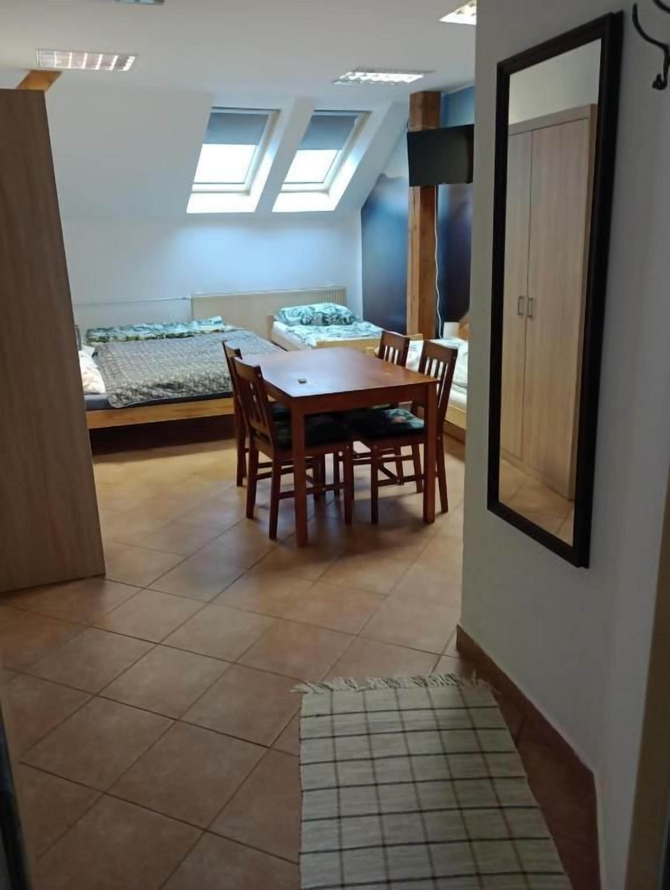A room with a dining table, chairs, a bed, and a wardrobe.