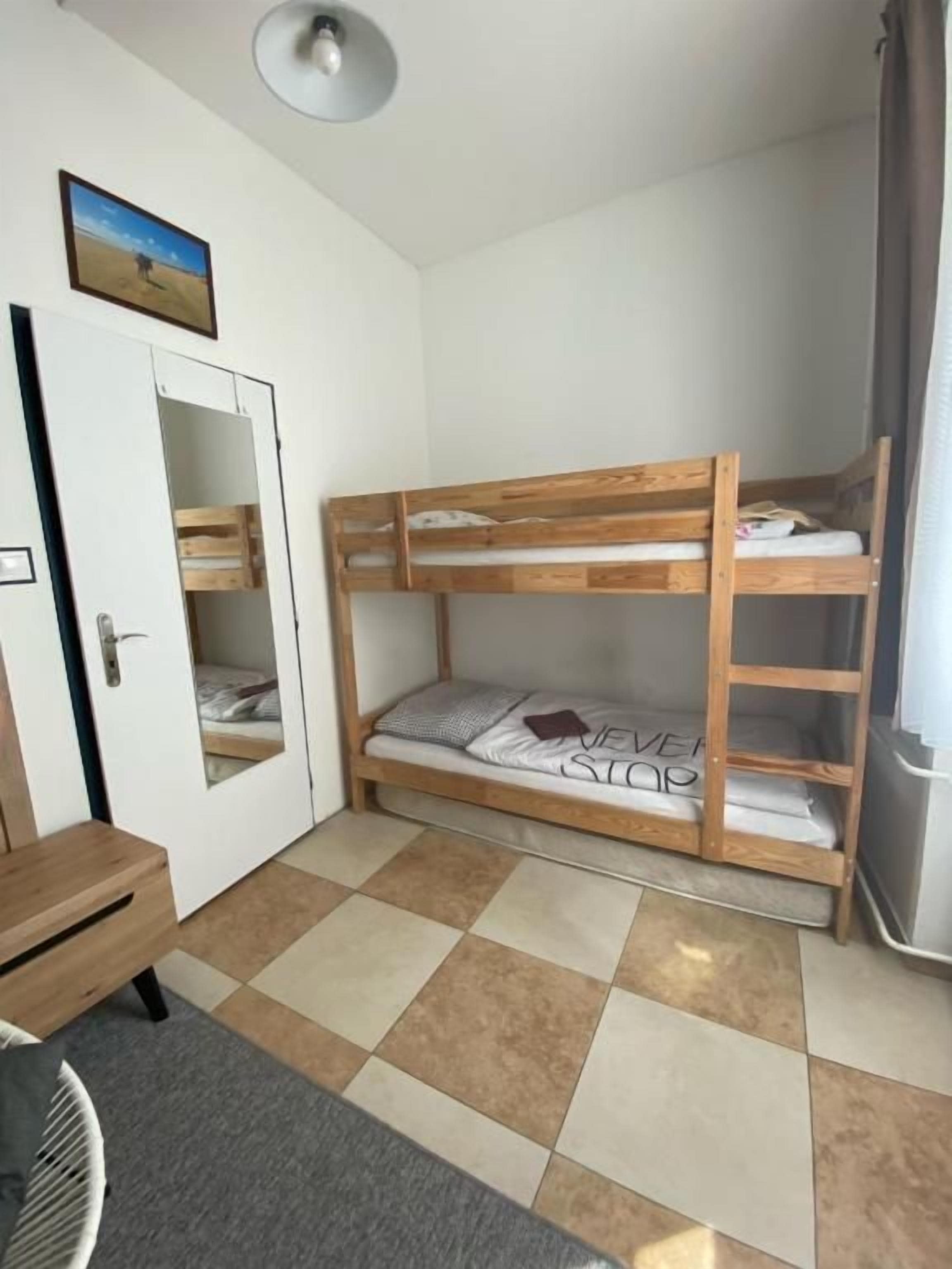 A compact room with a bunk bed, a desk, a chair, and a small table.