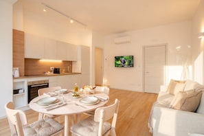 A modern living room with a dining area, a kitchen, and a TV mounted on the wall. - Casa Iris – Elegant Modern Retreat in the Heart of Bari (Bari)
