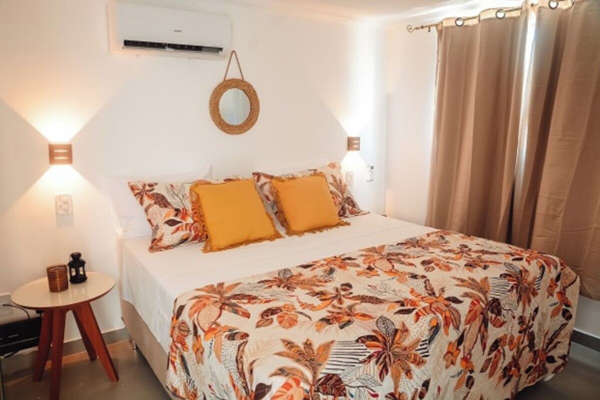 A bedroom with a bed, two wall-mounted lamps, a round mirror, and a small table with a lamp.