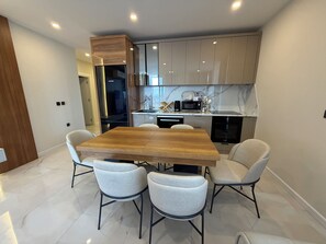 Une cuisine moderne avec une table et des chaises, des appareils en acier inoxydable et un meuble en bois.