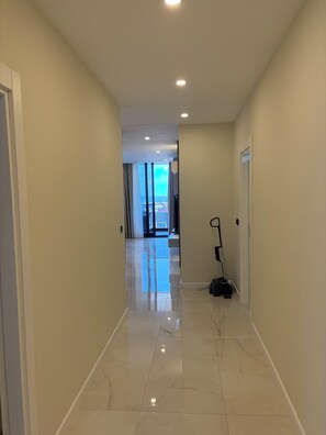 Un couloir d’hôtel donnant sur l’extérieur, un aspirateur et une porte sur la droite.