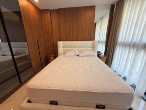 A modern bedroom with a large bed, wooden paneling, a nightstand, and a mirror. - Spacious 3-bedroom apartment in lovely Alanya with AC and gym access (Alanya)
