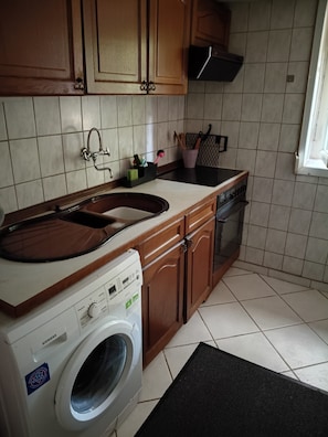 Una cocina equipada con lavadora, lavabo y armarios.