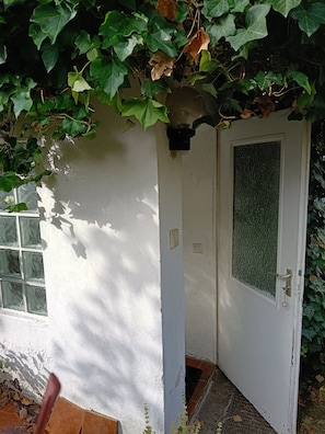 Una puerta blanca con un panel de vidrio texturizado, una ventana pequeña y un timbre.