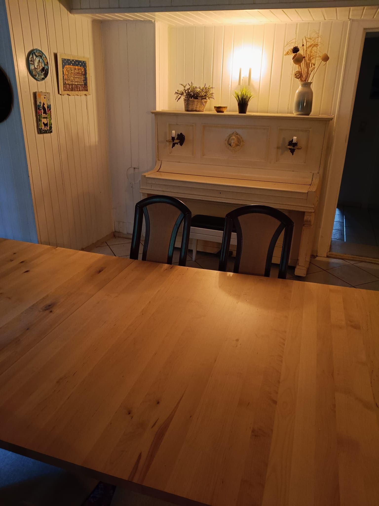 Una mesa de comedor de madera con cuatro sillas, un aparador blanco con adornos y una obra de arte colgada en la pared.