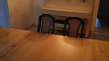 Una mesa de comedor de madera con cuatro sillas, un aparador blanco con adornos y una obra de arte colgada en la pared.