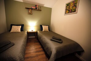 A twin room with two beds, a nightstand, a lamp, a bookshelf, and a painting on the wall. - A NEW MANOR for families & friends (up to 20 people), surrounded by nature (Vėžionys)