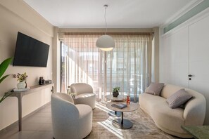 A modern living room with a sofa, armchairs, a coffee table, and a television mounted on the wall. - Urban Living Home | Cozy Retreat (Agios Onoufrios)