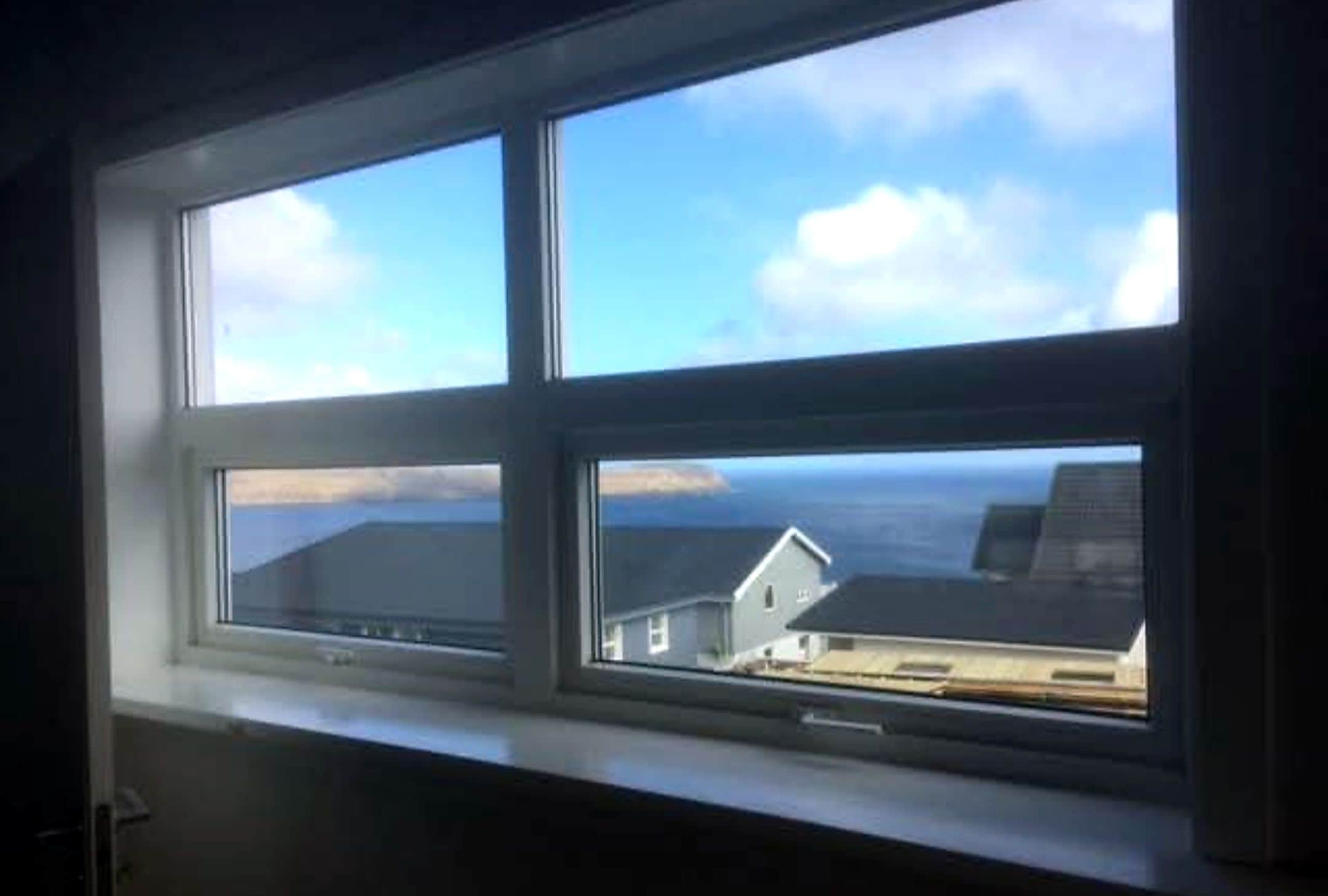 A window with a view of a building and a body of water.