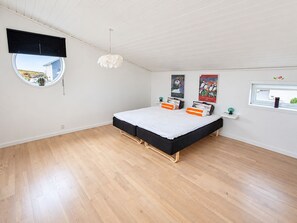 A bedroom with a bed, a round window, and artwork on the walls. - Ovaragøta 60 (Hoyvík)