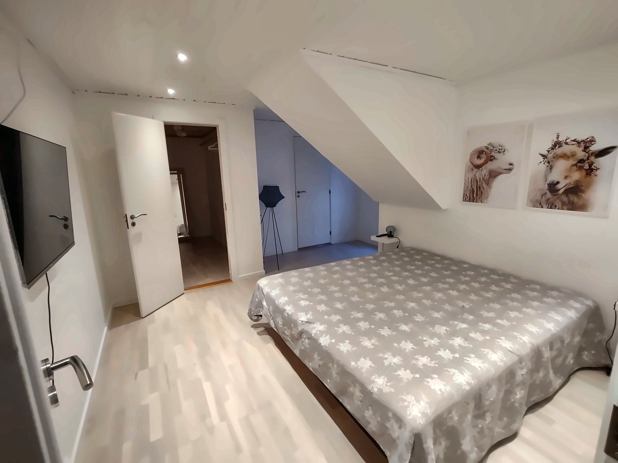 A bedroom with a bed, a TV, and a staircase leading to an upper level.
