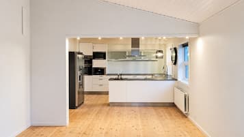 A modern kitchen with white cabinetry, stainless steel appliances, and a wooden floor.