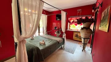 Une pièce avec un lit, une fenêtre avec des rideaux rouges, un vase de fleurs et un tableau au mur.