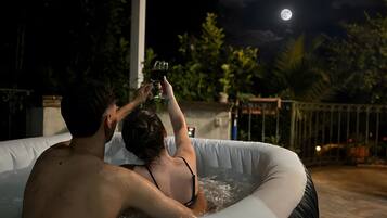 Un couple dans un jacuzzi, avec la lune en arrière-plan.