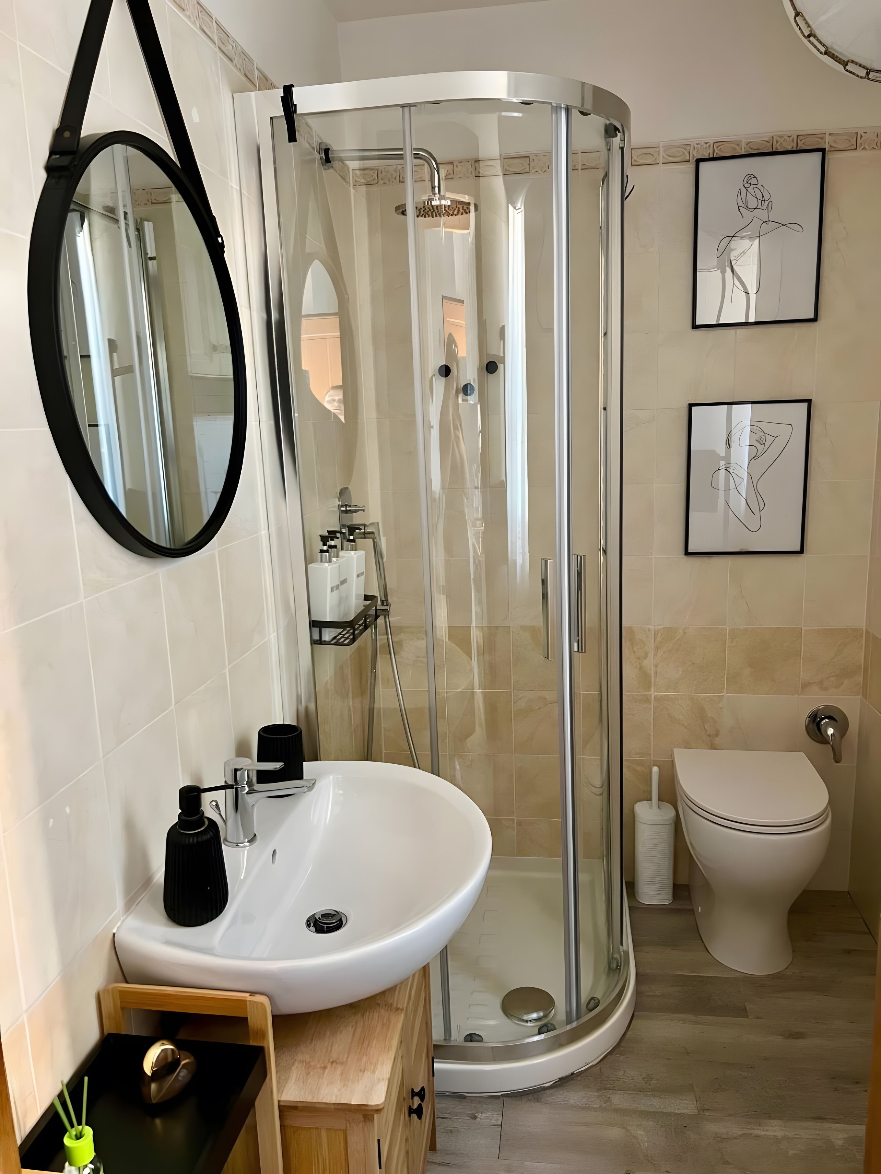 Un bagno con doccia vetrata, lavandino bianco, WC e opere d'arte appese al muro.
